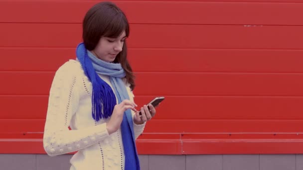Κοπέλα γυναίκα που κρατά ένα τηλέφωνο smartphone σε ένα σακάκι και κασκόλ κοινωνικά δίκτυα μέσων μαζικής ενημέρωσης — Αρχείο Βίντεο