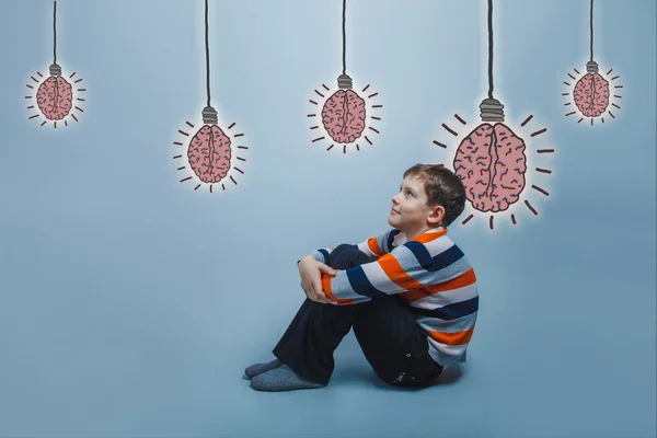 Adolescent boy sitting on the floor hugging his knees smiling lo — Stock fotografie