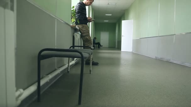 Estudiante de pie en el teléfono inteligente de la ventana Wi Fi acceso a Internet en el pasillo de la Universidad — Vídeo de stock