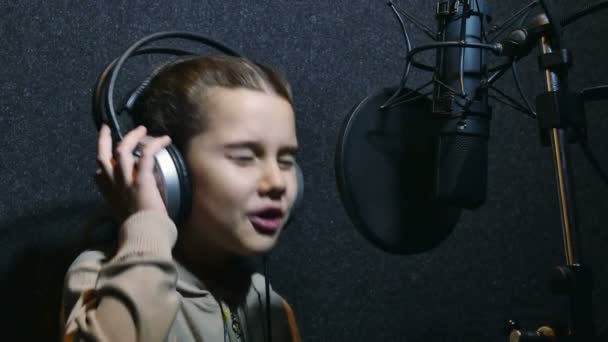 Adolescente chica en auriculares cantando en un micrófono estudio de grabación — Vídeos de Stock