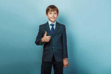 a boy of twelve  European appearance in a suit  thumbs up on a g
