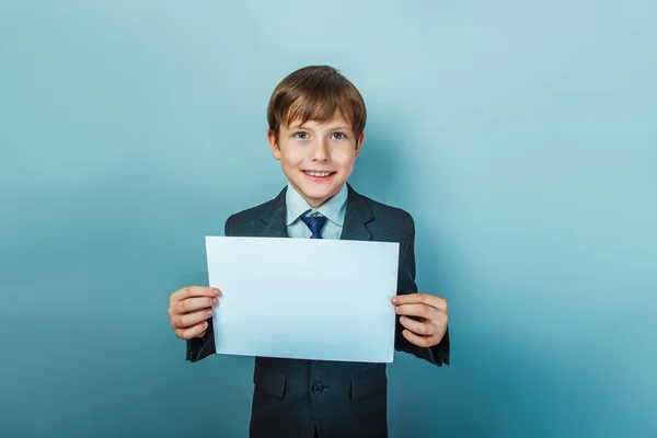 A boy of twelve European  appearance in a suit  holding a blank — Stock Photo, Image