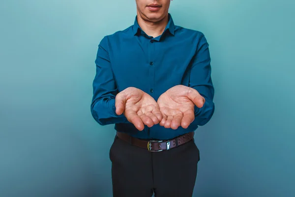 Un uomo volto di essere visto tenersi per mano davanti a un backgroun grigio — Foto Stock