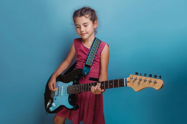 Mädchen europäische Erscheinung zehn Jahre spielen Gitarre auf einem blauen — Stockfoto