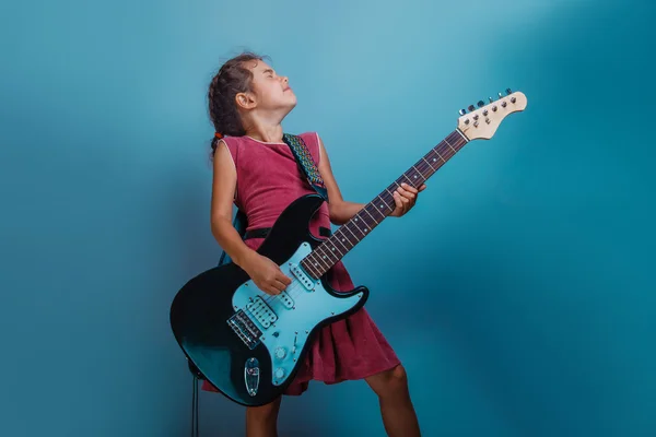 Girl  European appearance ten years  playing guitar on a blue ba — Stock Photo, Image