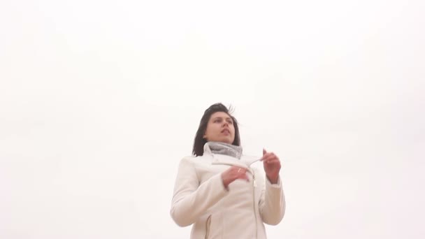 Mujer retrato chica en abrigo en blanco otoño fondo viento — Vídeos de Stock