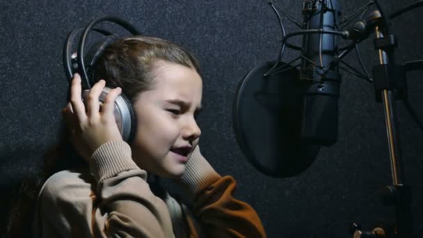 Menina adolescente em fones de ouvido cantando em estúdio de gravação de microfone — Vídeo de Stock