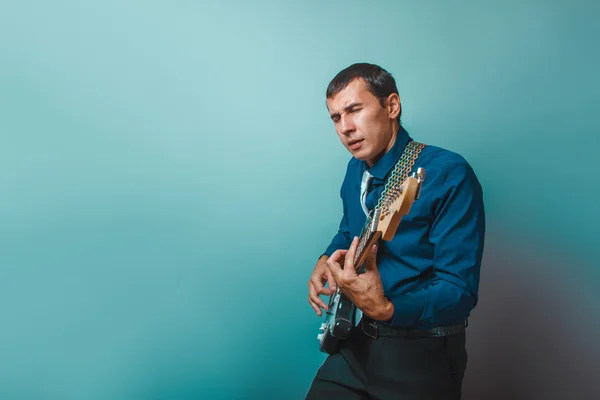 A man of European appearance thirty years of  playing guitar on — Stock Photo, Image