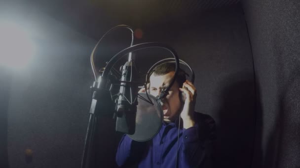 Muž zpěvák zpívá píseň ve studiu sluchátka — Stock video