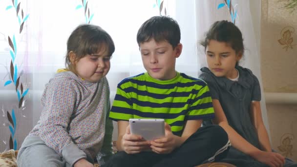 Kinderen spelen in de tablet meisjes en een jongen — Stockvideo