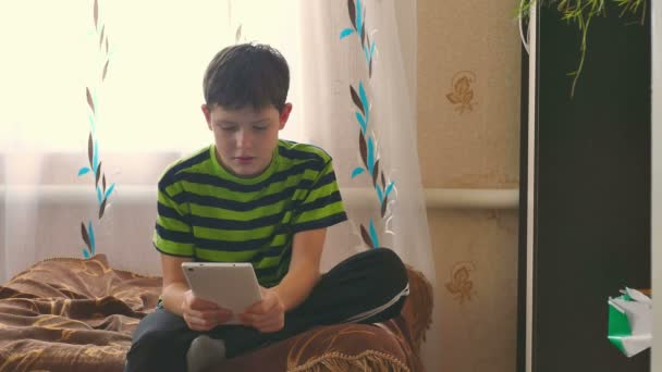 小男孩平板电脑玩游戏浏览互联网，坐在沙发上 — 图库视频影像