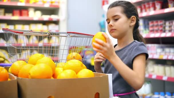 Menina com tablet no supermercado para comprar laranja — Vídeo de Stock