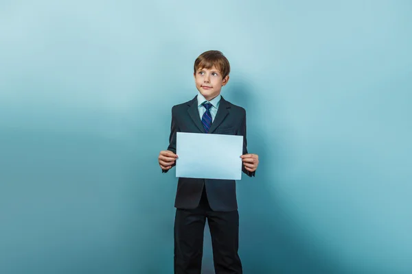 A boy of twelve  European appearance in a suit  holding a blank — 图库照片