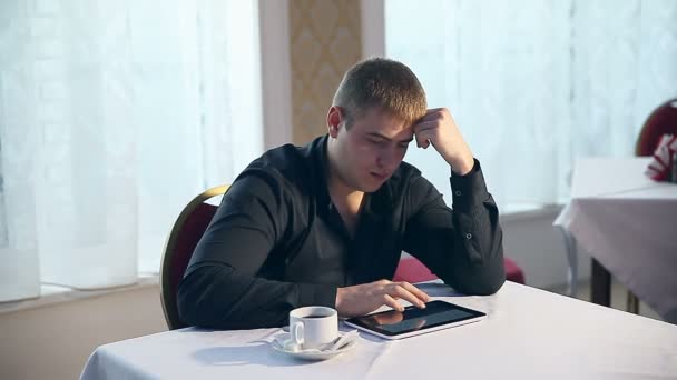 Homem em um café com seu tablet bebendo café — Vídeo de Stock