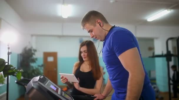 Homme sur tapis roulant dans la salle de gym Fille sur tapis roulant entraîneur, sport un mode de vie sain — Video