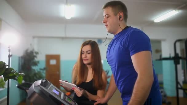 Mann auf dem Laufband im Fitnessstudio Mädchen auf dem Laufband Trainer, Sport einen gesunden Lebensstil — Stockvideo