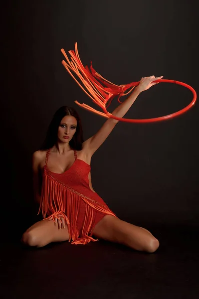 Sexy Brunetka Červeném Obleku Gymnastickou Obručí Tmavém Pozadí Studiu — Stock fotografie