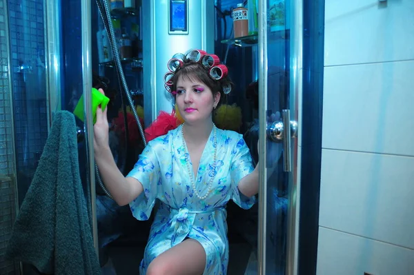 young sexy housewife in curlers washes the shower