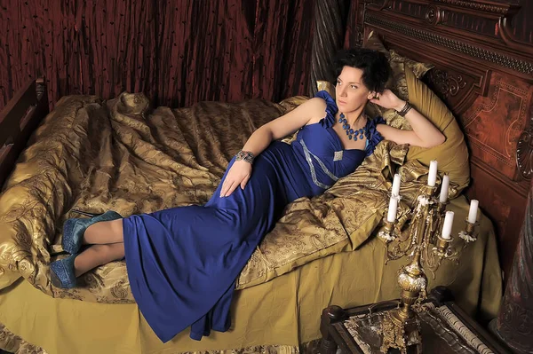 Μελαχρινή Κυρία Μπλε Φόρεμα Στο Κρεβάτι Vintage Εσωτερικό — Φωτογραφία Αρχείου