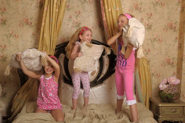 三个小女孩在床上玩耍 和枕头打斗 — 图库照片