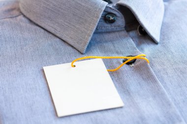 Fiyat etiketi ve sarı-turuncu etiketli küçük gri çizgili erkek gömleği