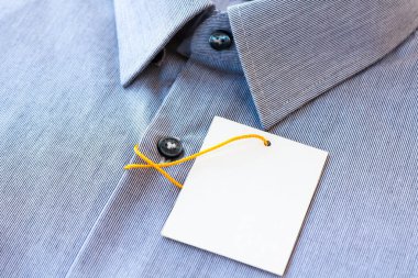 Fiyat etiketi ve sarı-turuncu etiketli küçük gri çizgili erkek gömleği