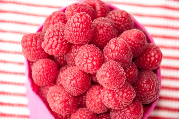 Belles framboises dans un sac rose sur fond rayé — Photo