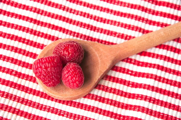 Raspberries in a wooden spoon on striped background from above — Stock Photo, Image