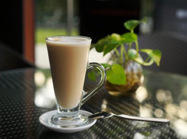 Cam tabakta bir kaşık ile latte ile. Kafede tablo.