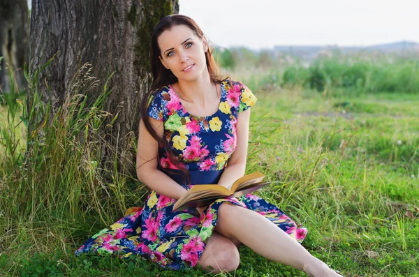 Όμορφη γυναίκα διαβάζει ένα βιβλίο στο πάρκο — Φωτογραφία Αρχείου
