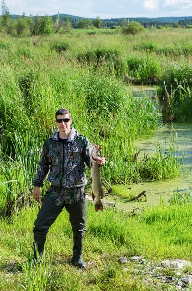 Visser met zijn snoek op de achtergrond van de natuur — Stockfoto