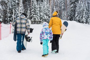 Baba, anne ve kız snowboardla dağ yamacına çıkıyorlar.
