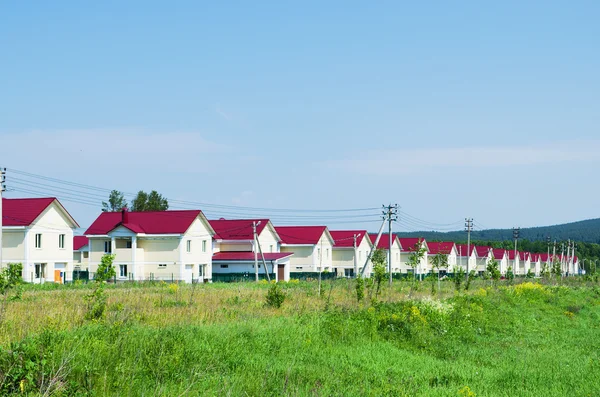 Nieuwe dorp van gelijkaardige huizen in zonnige zomerdag. Rusland — Stockfoto