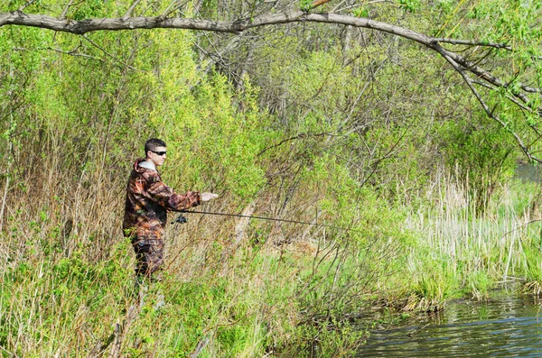 The fisherman catches a fish on spinning — Stock Photo, Image