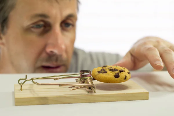 Man Looking at Cookie In Rat Trap Stock Image