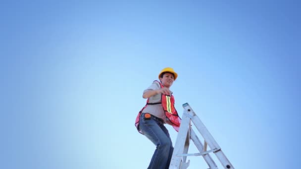 Arbeiterin klettert mit erhobener Hand auf Leiter — Stockvideo