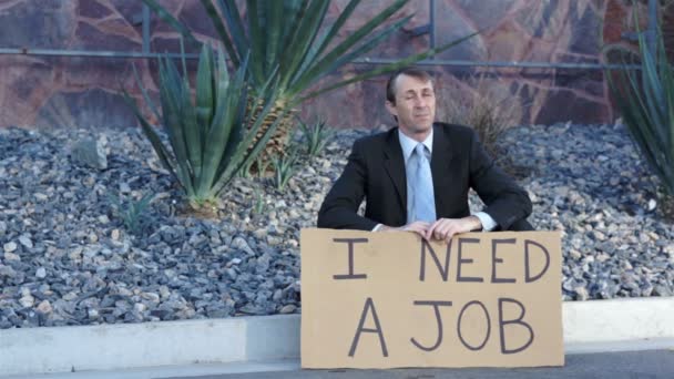 Geschäftsmann sitzt und braucht ein Jobschild — Stockvideo