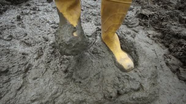 Резиновые сапоги, шагающие в грязи — стоковое видео