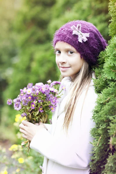 Small girl with seasonal flowers — Stock Photo, Image