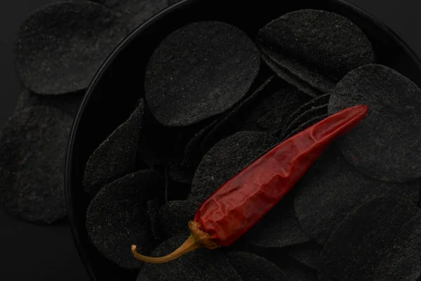 Patatas fritas negras y pimientos rojos sobre fondo negro — Foto de Stock