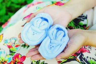 Bebek Patiği tutan bir göbek ile hamile kadın.