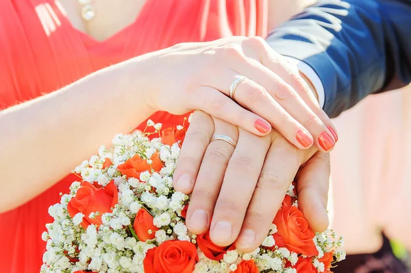 Mãos e anéis no buquê de casamento — Fotografia de Stock