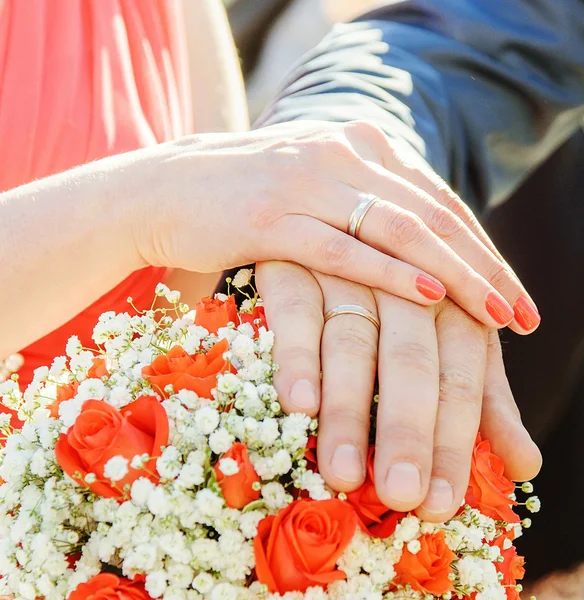 Mãos e anéis no buquê de casamento — Fotografia de Stock