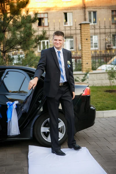 Le marié sort de la voiture sur un chemin blanc pour une cérémonie de mariage — Photo