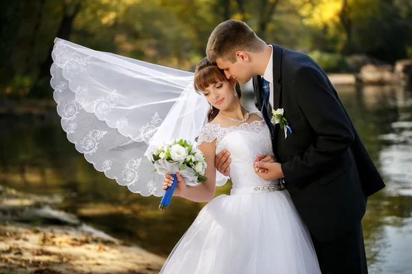 Lo sposo e la sposa con un velo svolazzante che cammina sulla spiaggia — Foto Stock