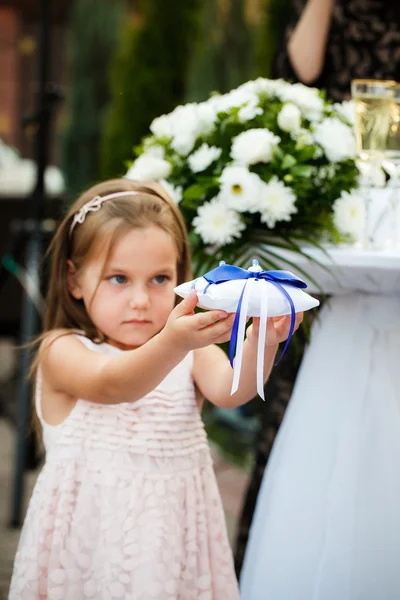 Dziewczyna trzyma poduszkę z obrączki podczas ceremonii ślubnej — Zdjęcie stockowe