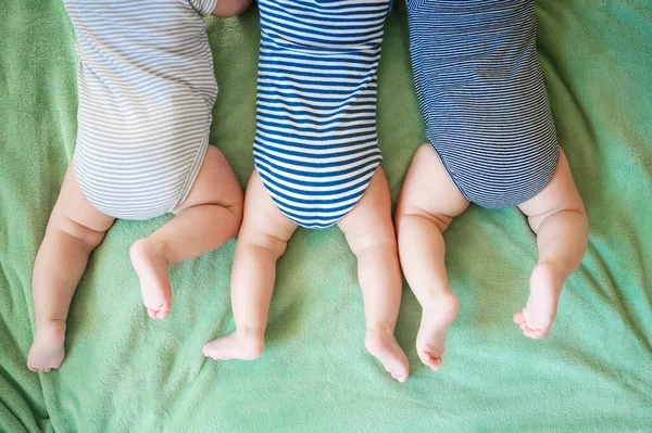 新生三胞胎躺在毛毯上的肚子上 — 图库照片