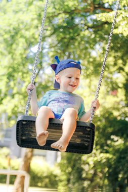 Küçük çocuk zincirli salıncakta sallanıyor.