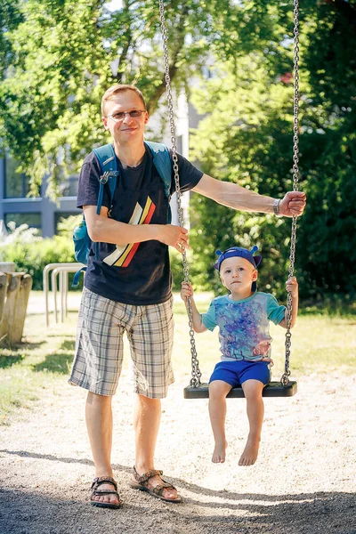 父は公園でスイングに息子 を押して — ストック写真