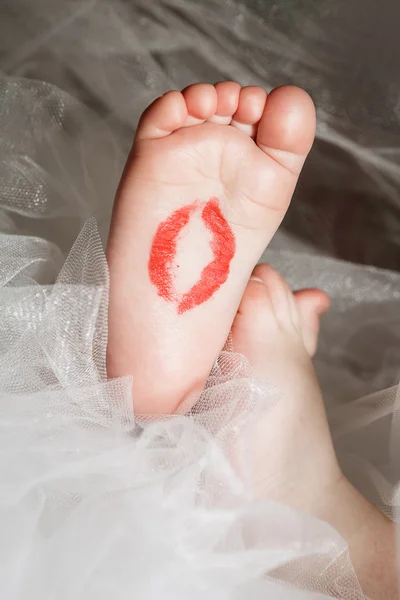 Pés de bebê com um traço de batom vermelho de um beijo — Fotografia de Stock